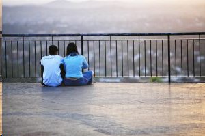 young couple sitting on roof of high rise